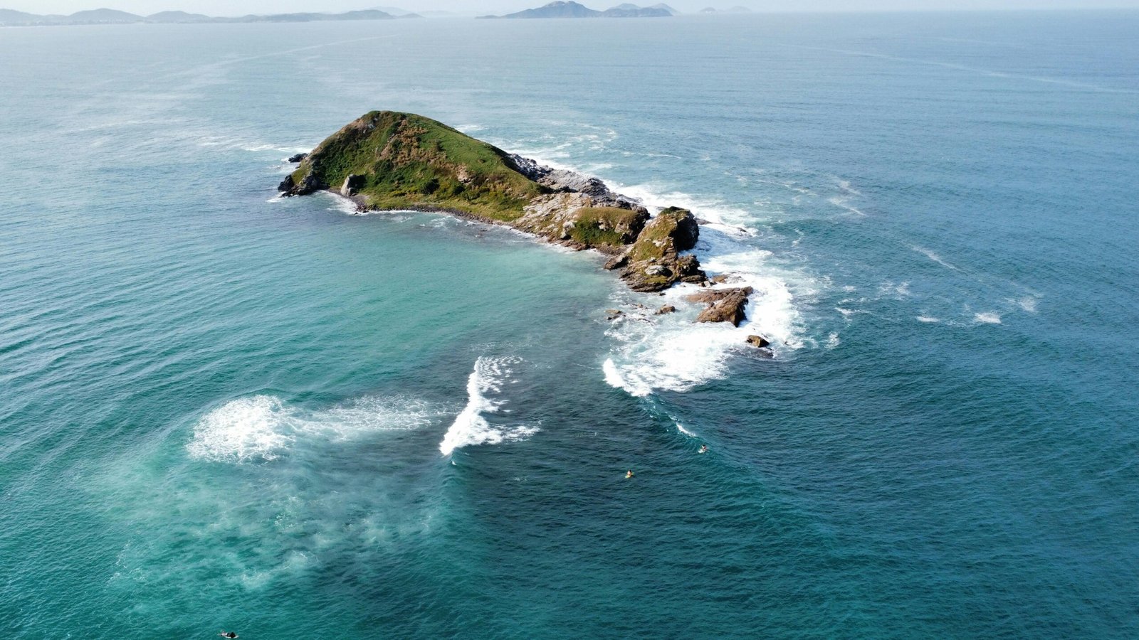 Stunning aerial view of a small island surrounded by turquoise ocean waves.